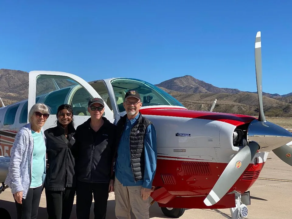 Mission volunteers standing beside a small airplane on a desert airstrip