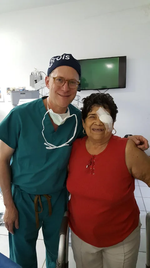 Dr. Perlman with a smiling patient wearing an eye patch after surgery