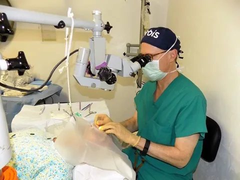 Dr. Perlman operating with a surgical microscope at a mission clinic