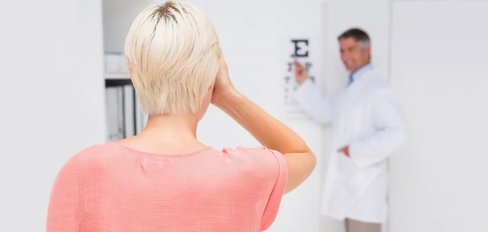Patient covering one eye while the doctor points to an eye chart