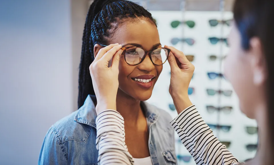 Smiling woman trying on new eyeglass frames with an optician